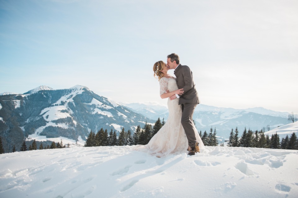 Bride and groom kissing in snowy mountains
