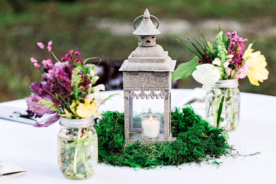 candle lit lantern table centerpiece with mason jar floral arrangements