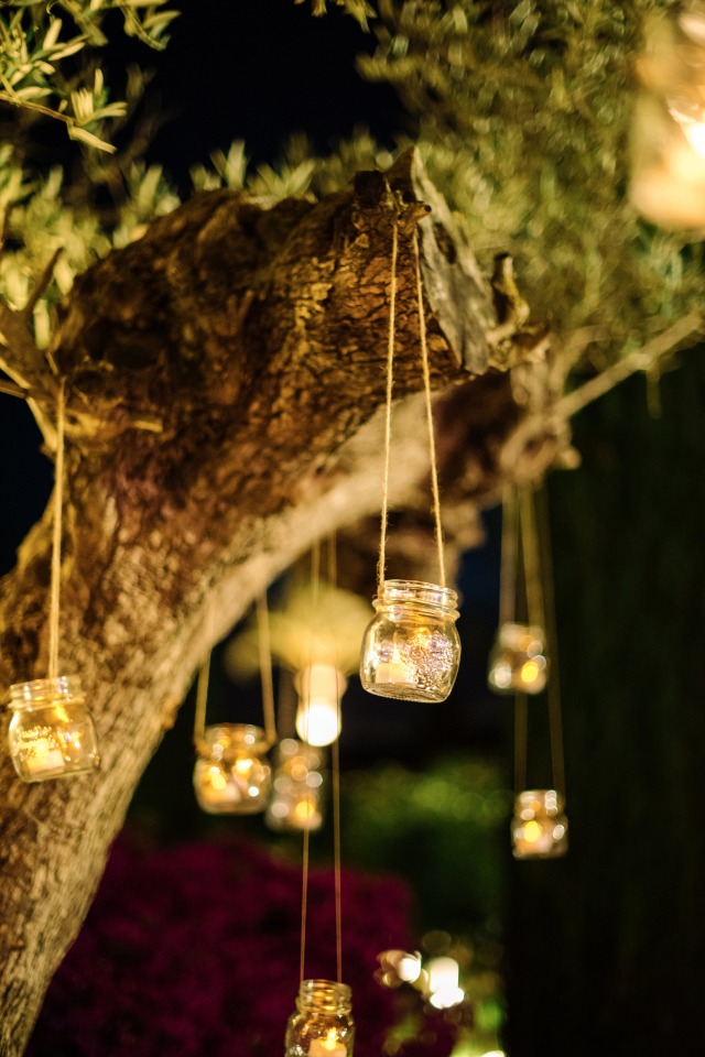candle lit mason jars hanging from garden trees