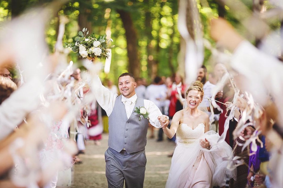 Happy couple joyfully exits wedding, showered with confetti