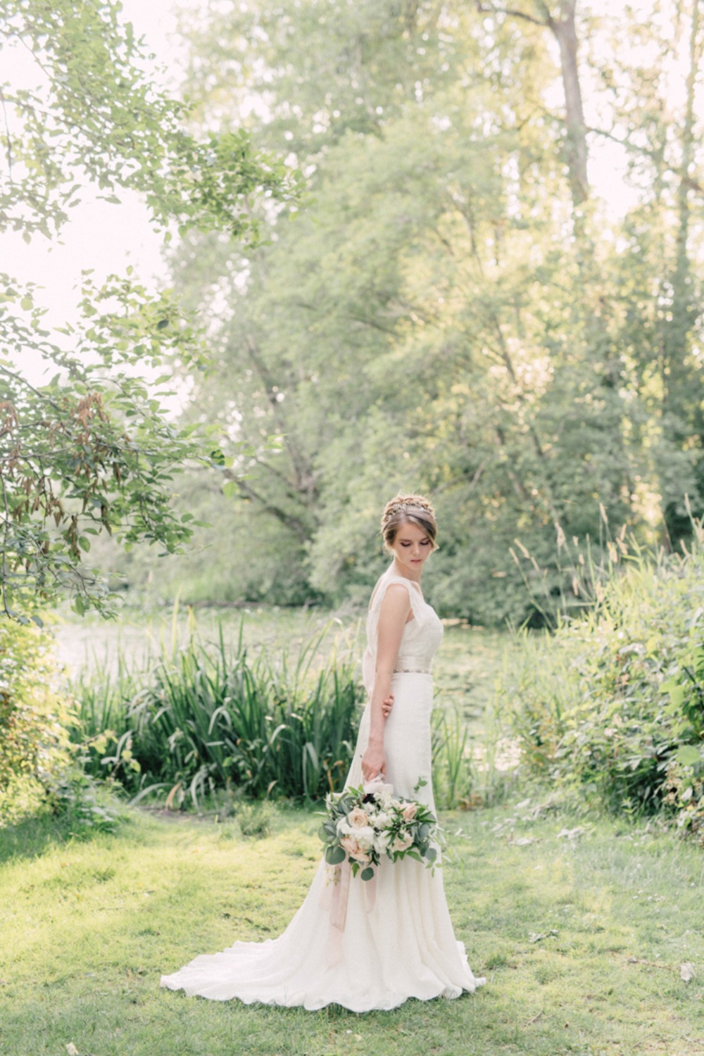Bride in flowing wedding dress with bouquet in nature scene