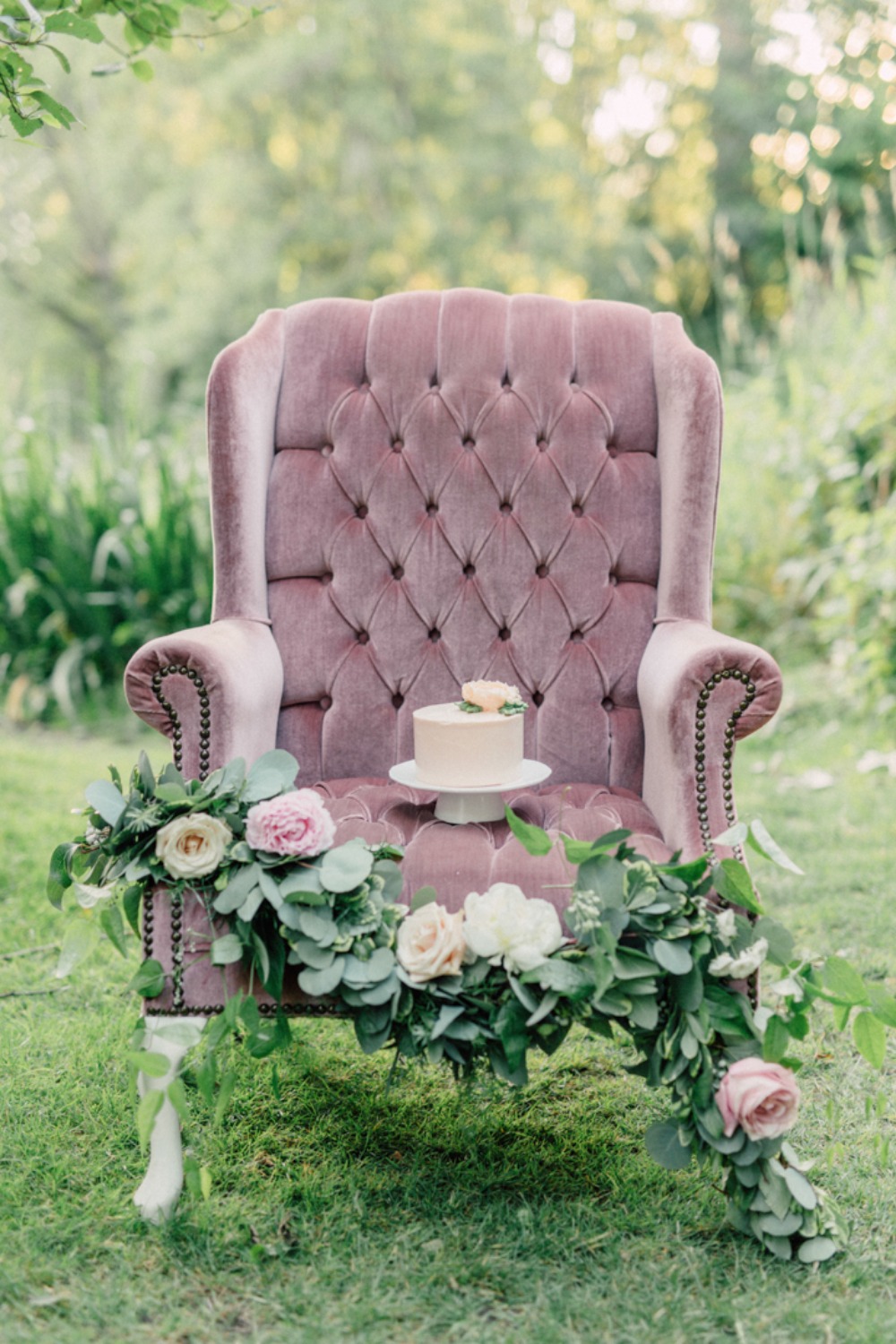 Pink velvet armchair with cake and floral decoration outdoors