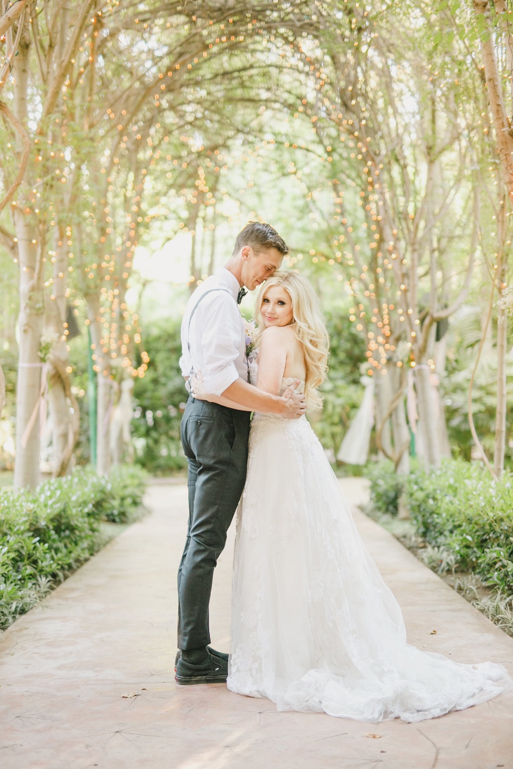 Romantic wedding couple embracing under a light-draped arbor