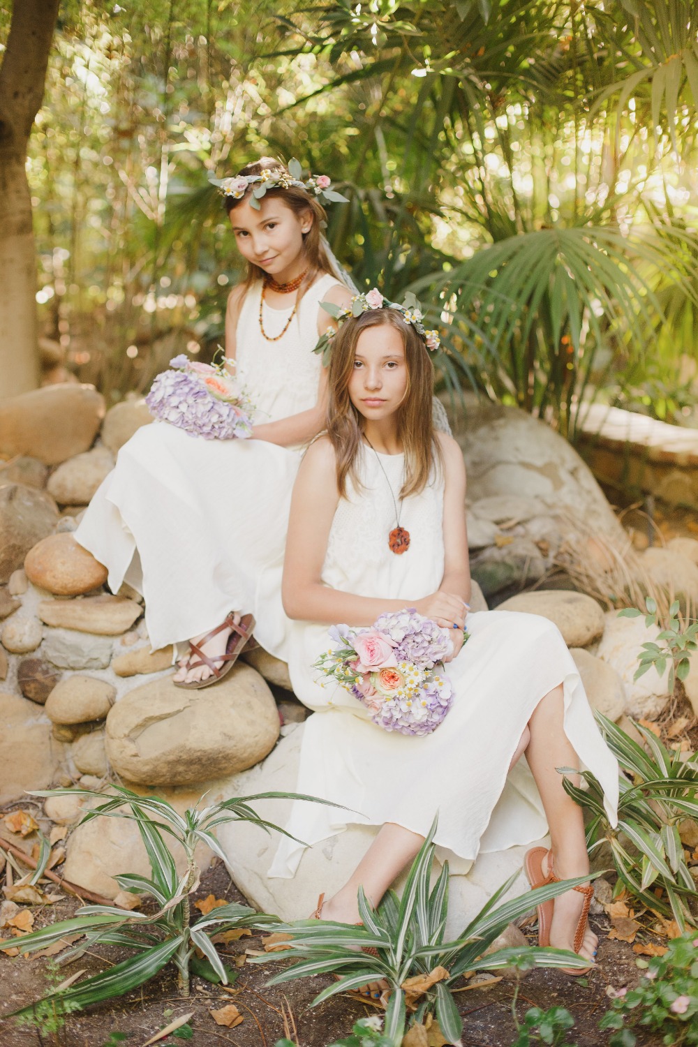 Two girls in flower crowns white dresses holding bouquets