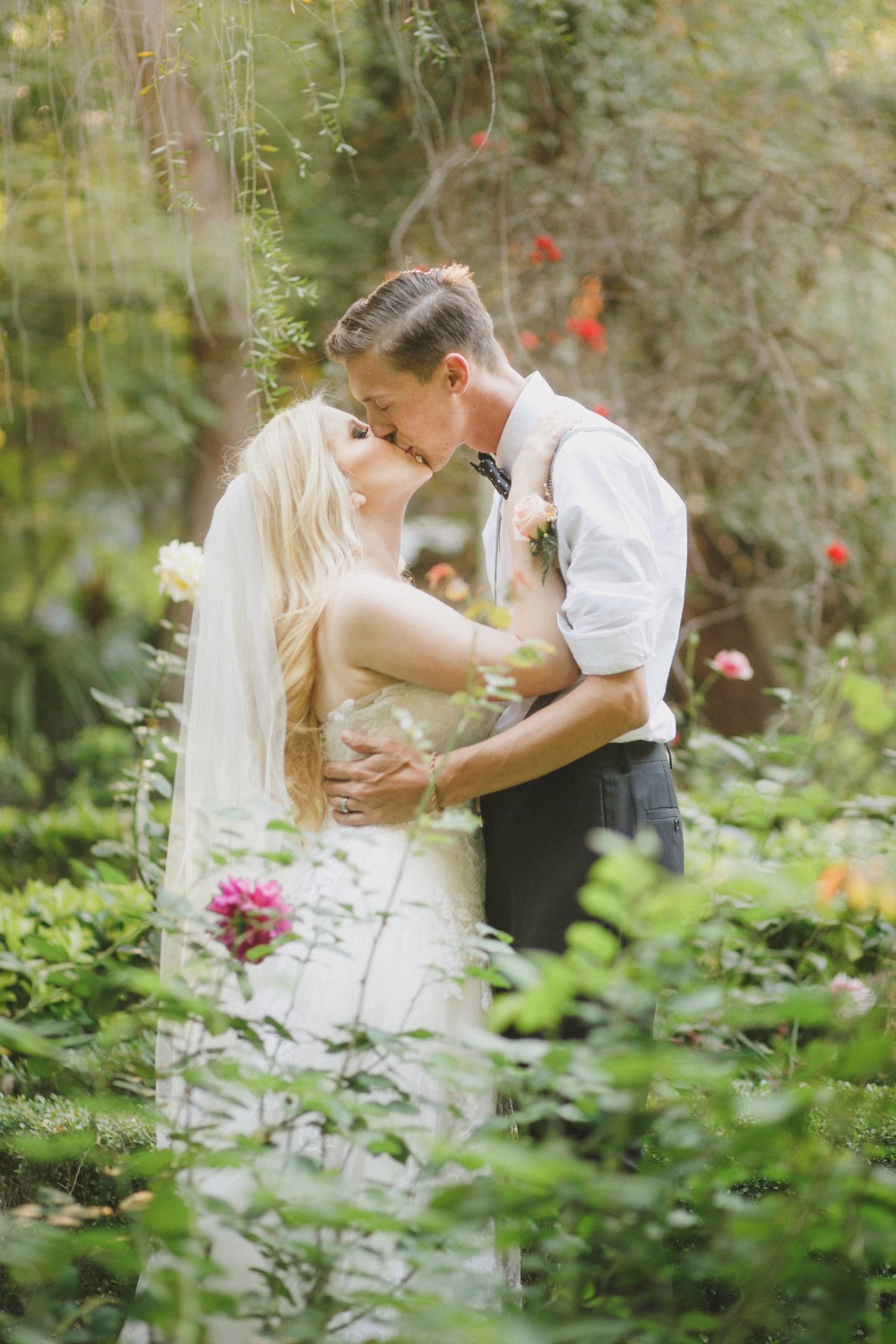 Newlywed couple sharing a kiss in a lush garden setting