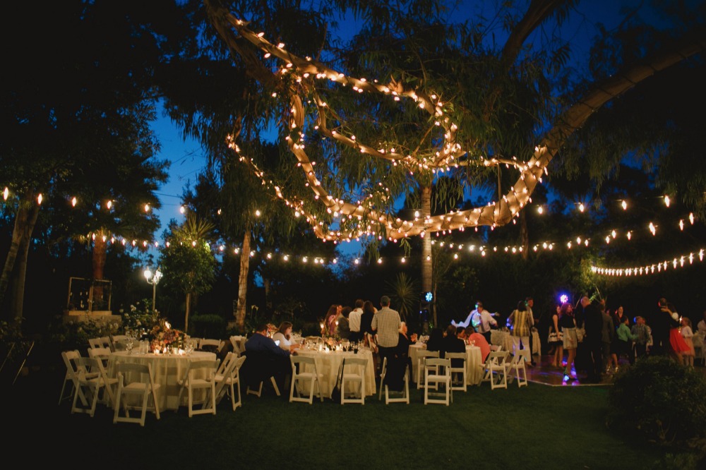 Outdoor wedding reception with string lights decorating a tree at night