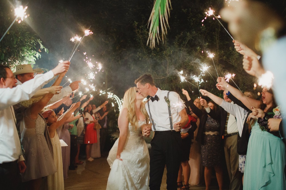 Newlyweds share a kiss under sparklers as guests celebrate their wedding