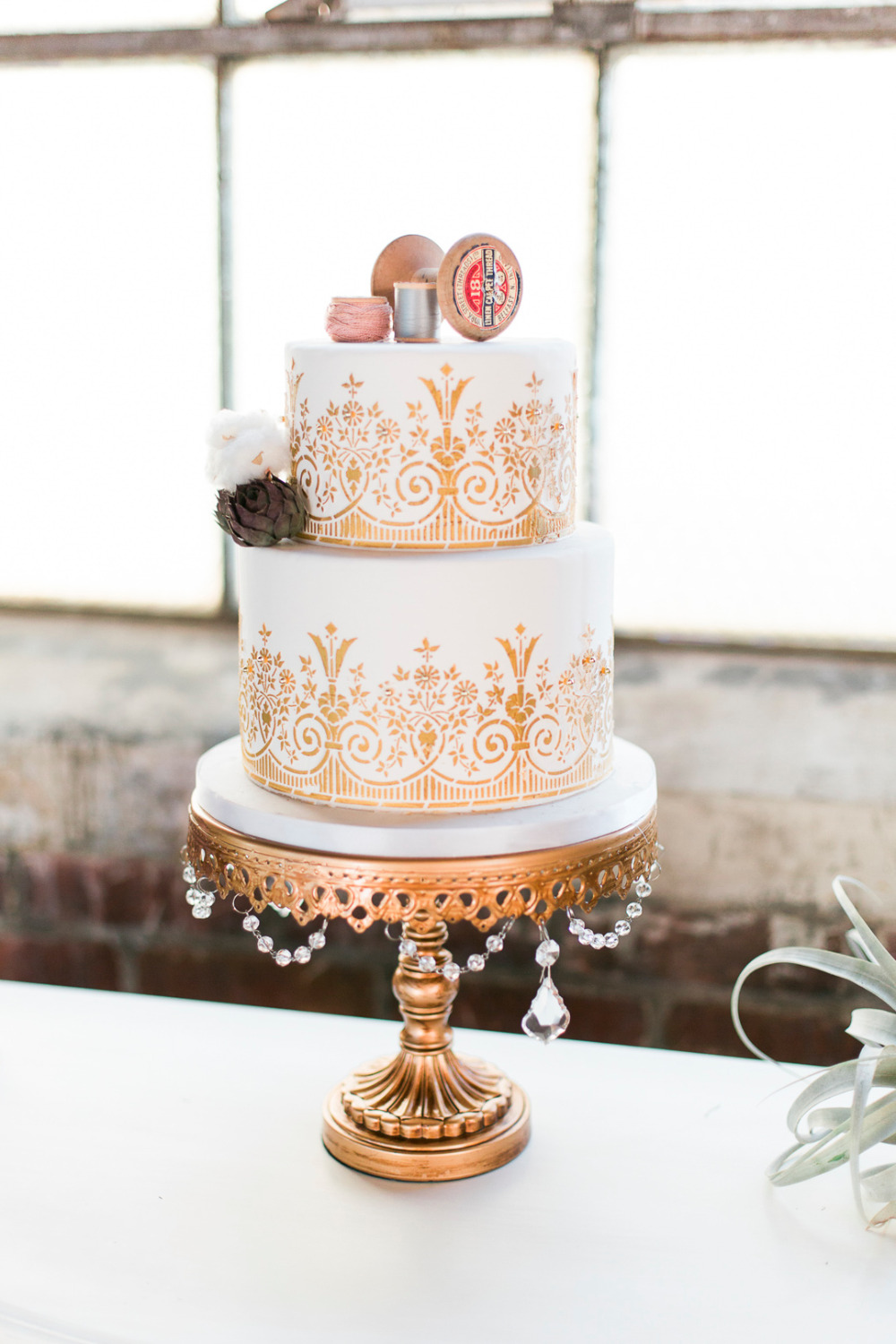 gold and white wedding cake with thread spools