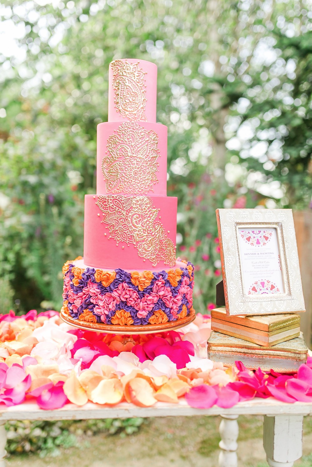 Grand four-tiered ombre fuchsia cake with intricate henna piping