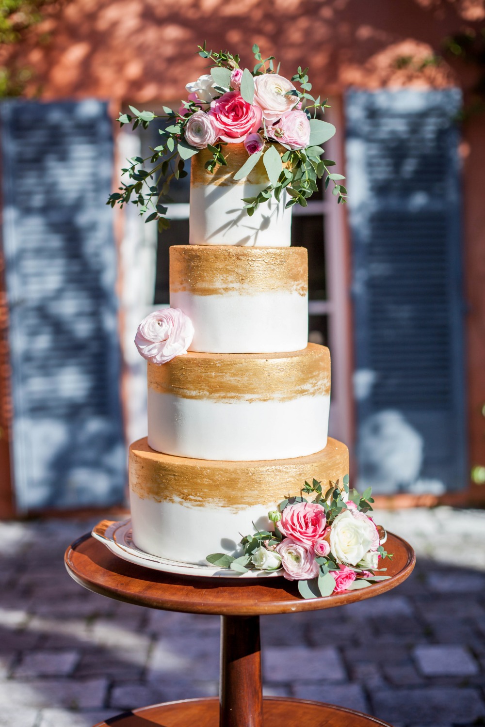 Gold and white wedding cake with pink roses