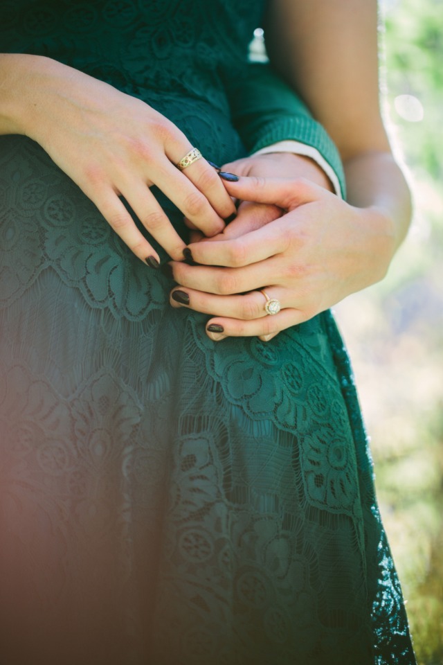 Couple holding hands with wedding rings and green dress