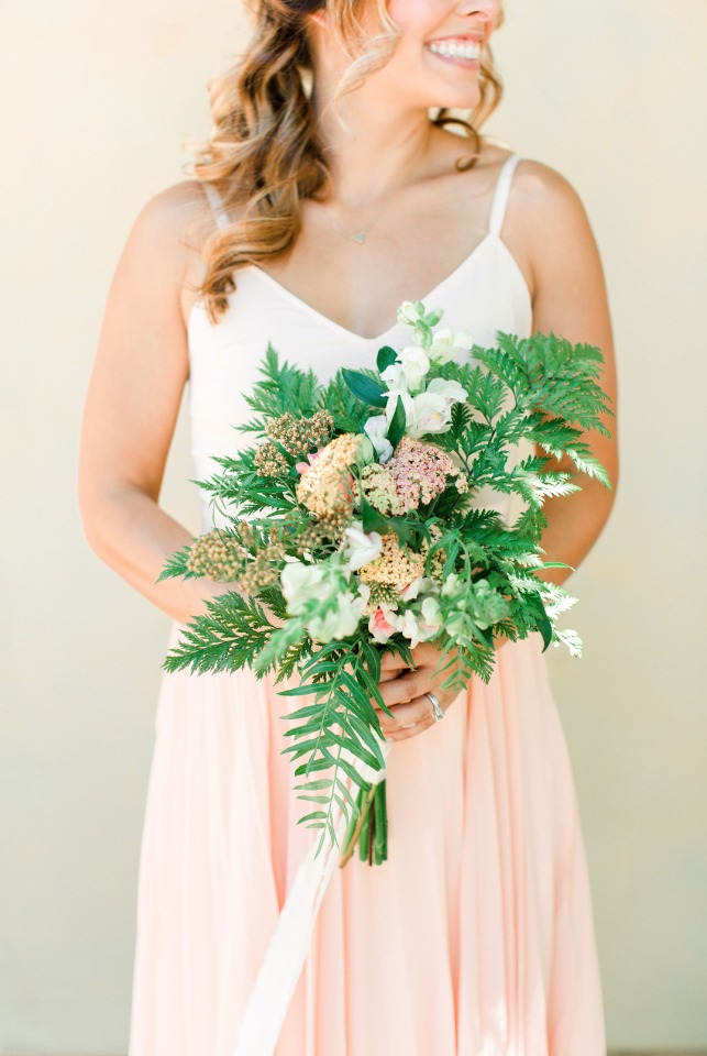 Bridesmaid in pink dress holding a lush green and blush bouquet
