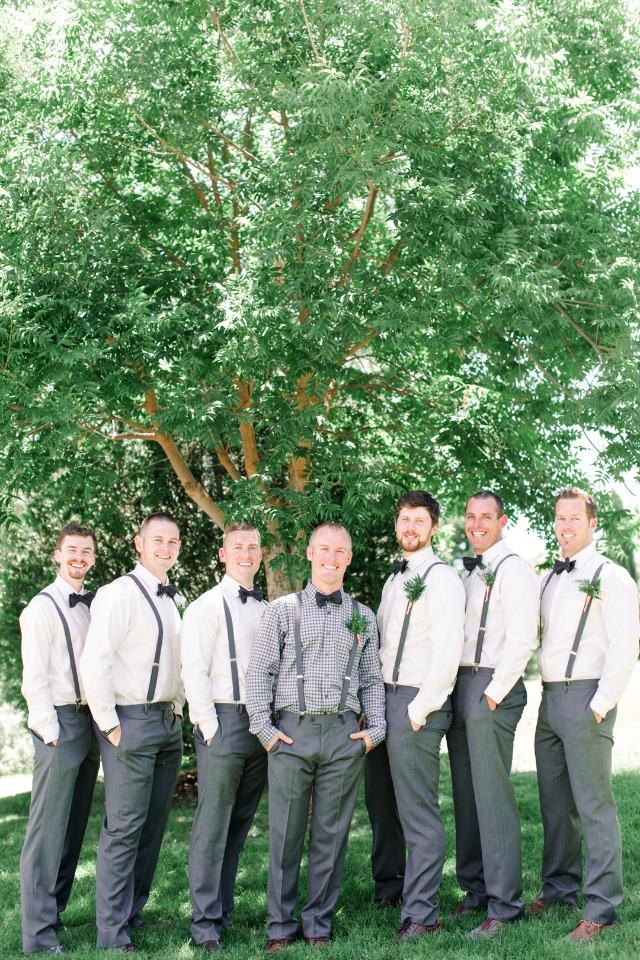 Groomsmen in gray suits and suspenders pose under a tree