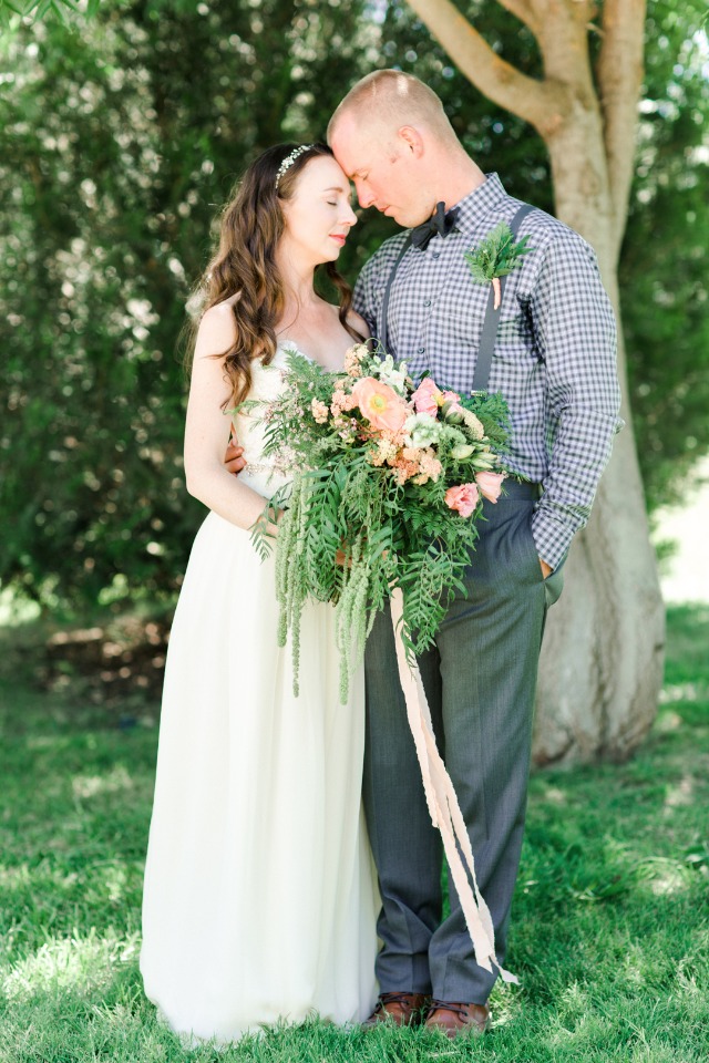 Bride and groom embrace with flowers outdoor wedding
