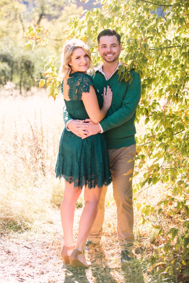 Smiling couple embrace outdoors in green dress and sweater