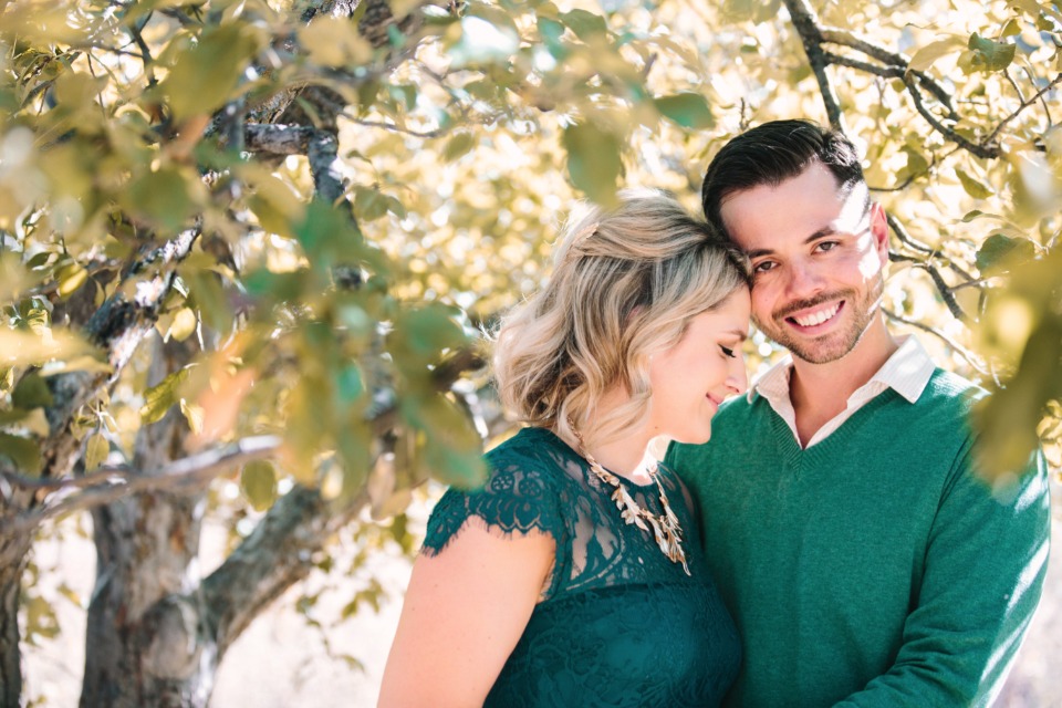 Affectionate couple smiling under leafy tree in park