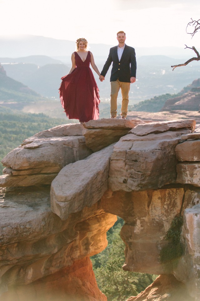 Couple holding hands on mountain rock arch scenic view