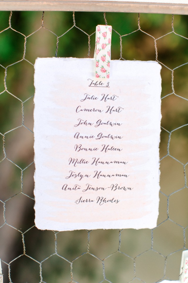 Elegant wedding seating chart card held by a decorated clip