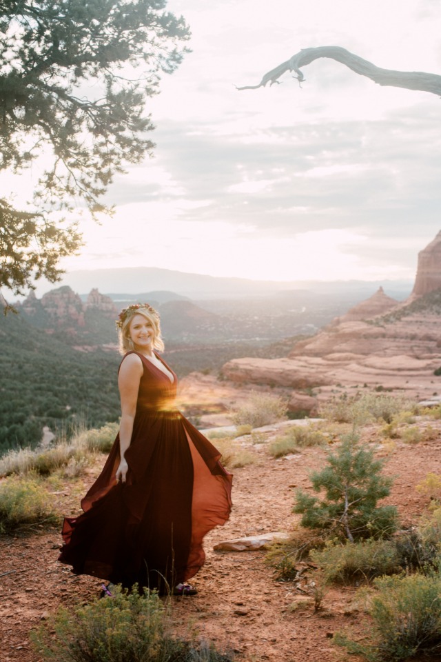 Woman in flowing red dress enjoys desert sunset view