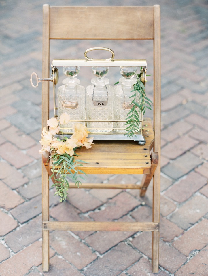 Vintage bar bottles on a wooden chair with floral arrangements