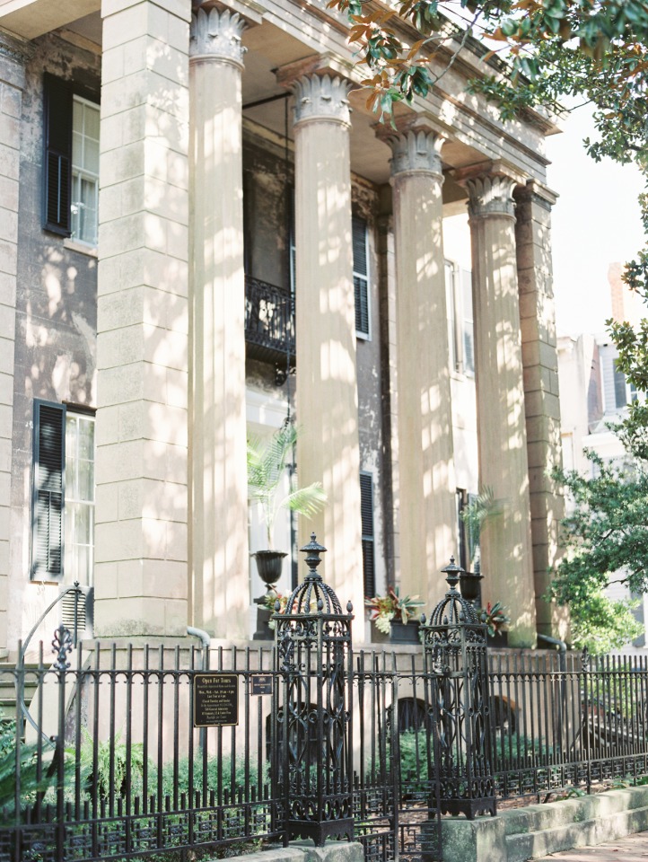 A historic building with grand columns and decorative black iron fence