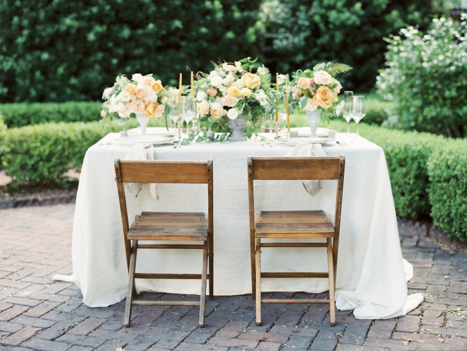Elegant outdoor dining table setting with flowers and chairs