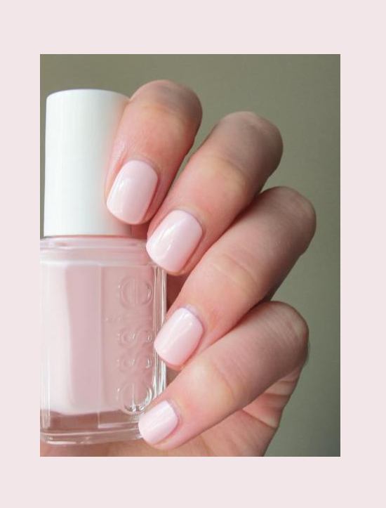 Pink nail polish bottle and hand with painted nails