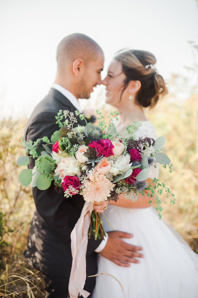 Romantic newlyweds embrace wedding flowers outdoor
