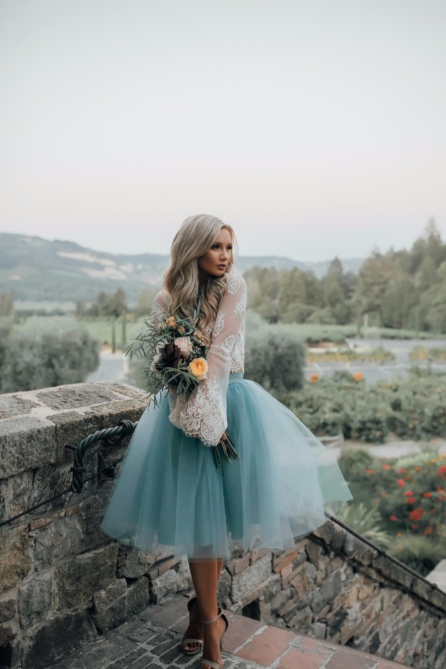Woman in teal tulle skirt and lace top, holding flowers
