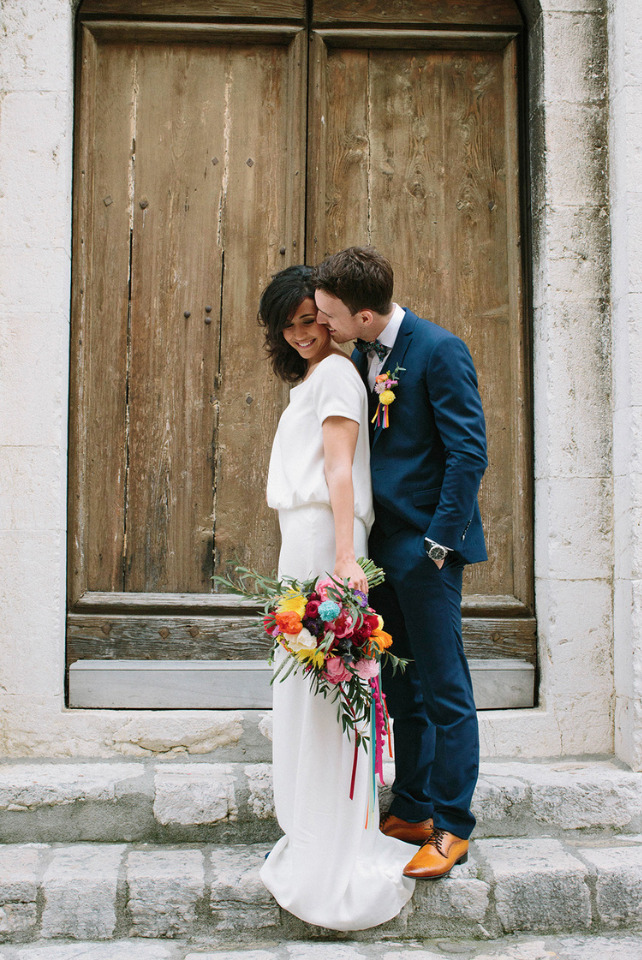 Happy couple embracing near wooden door, colorful bouquet