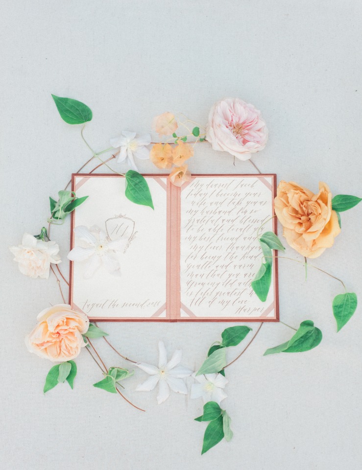 Wedding invitation surrounded by flowers and leaves on a white background