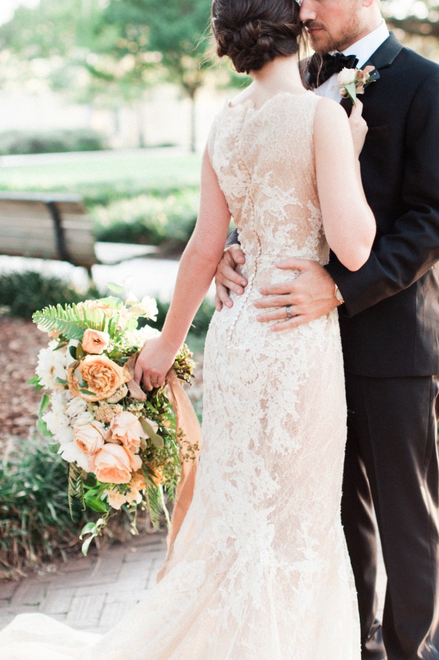 Bride and groom embracing during a wedding with bouquet and lace dress