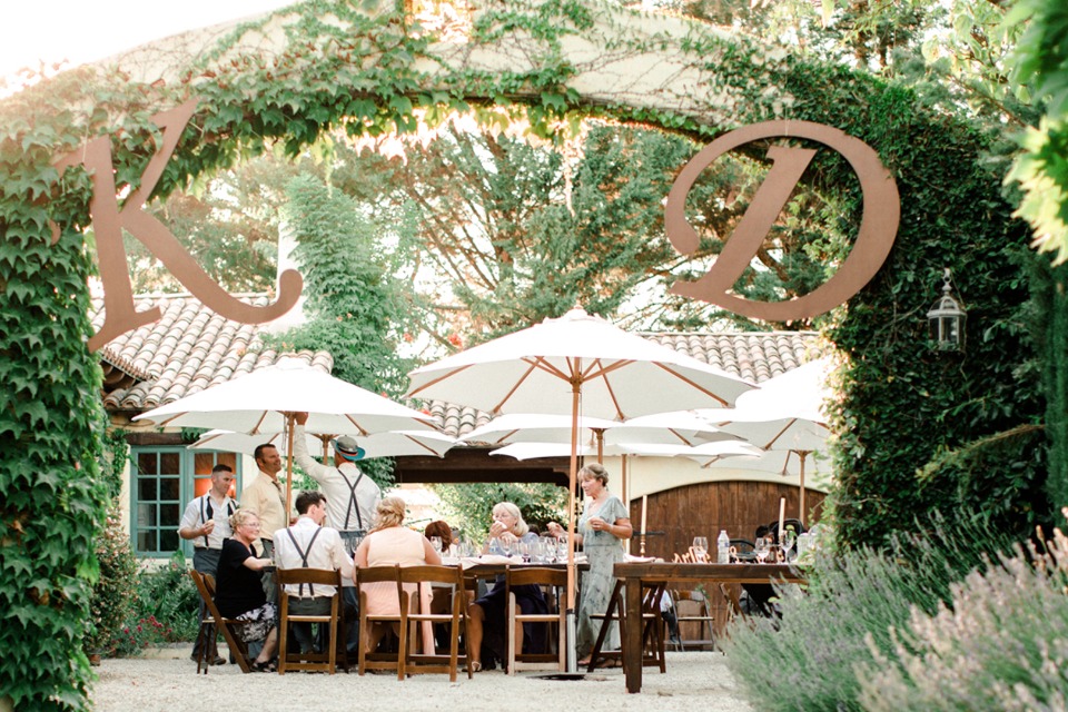 Outdoor wedding reception with vine archway and white umbrellas