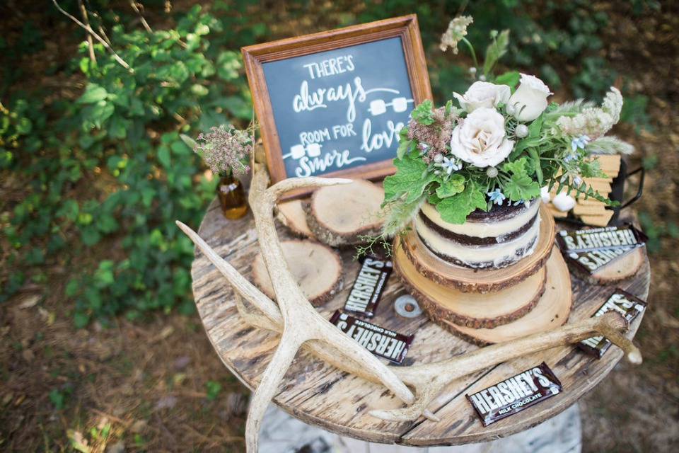Rustic woodland smores dessert table with cake and flowers