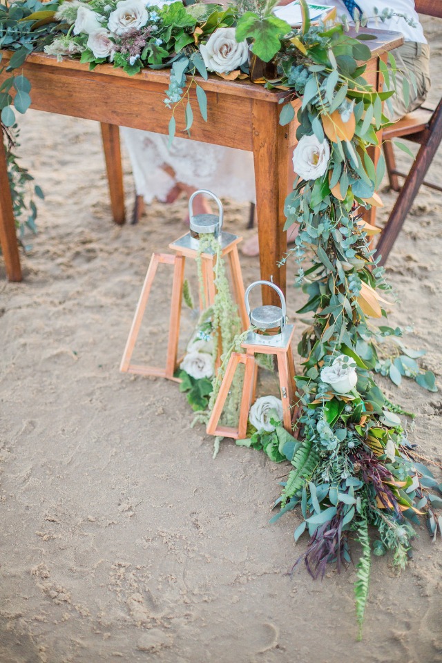 Lush floral garland decorates beach wedding table