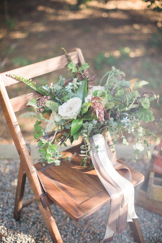 Bridal bouquet on wooden chair with flowing ribbon