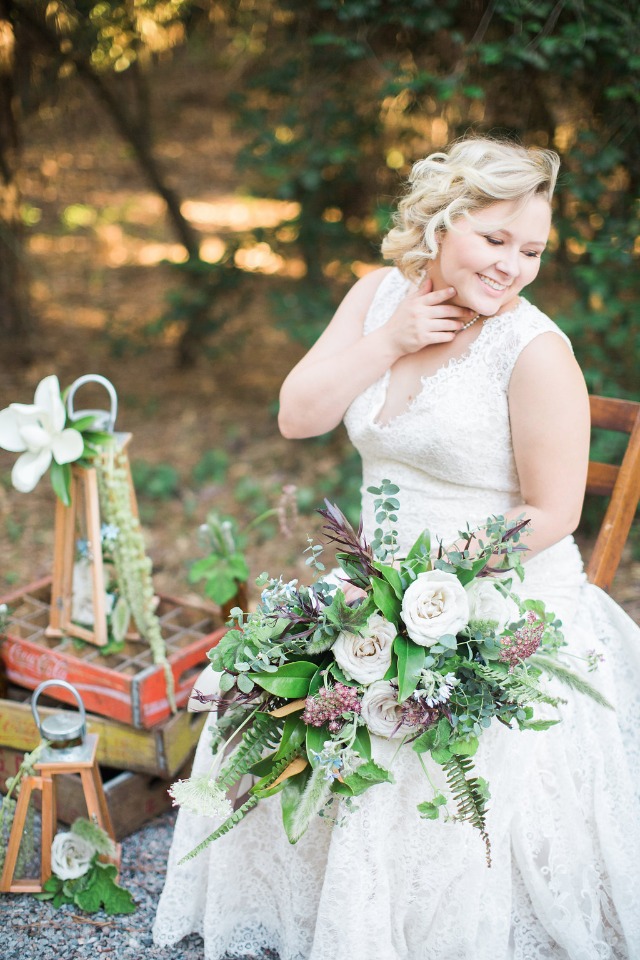 Blonde bride in lace dress holding her flower bouquet