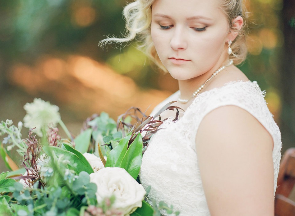 Bride in lace dress holding floral bouquet closeup