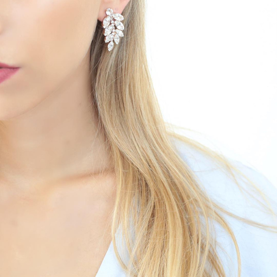 Woman wearing leaf shaped white rhinestone earrings