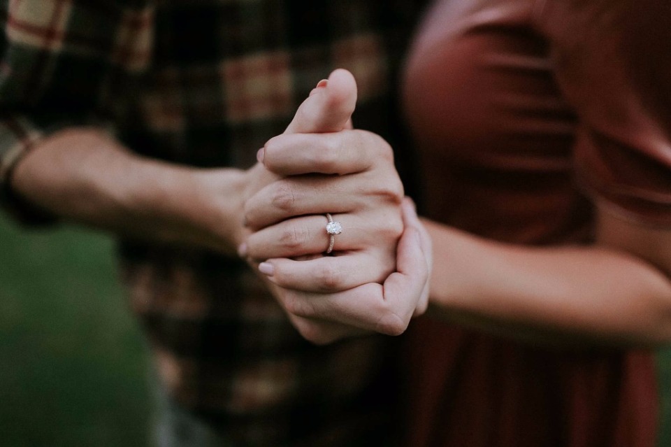 Close-up of hands clasped, showcasing engagement ring