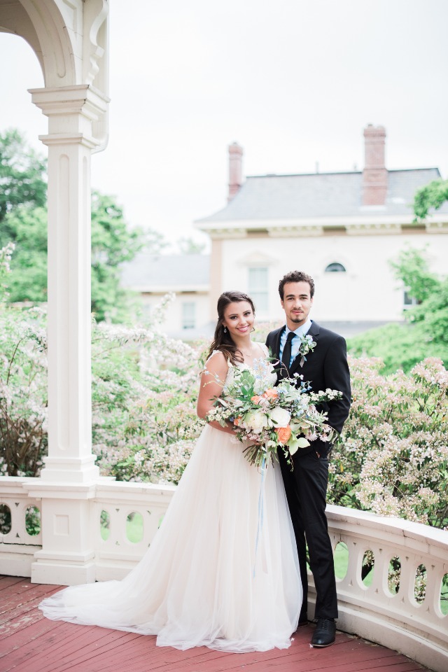 Bride and groom pose with bouquet on their wedding day