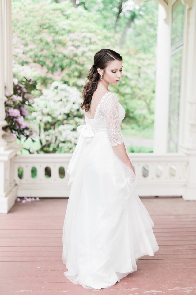 Elegant young woman in a beautiful white lace dress on a garden porch