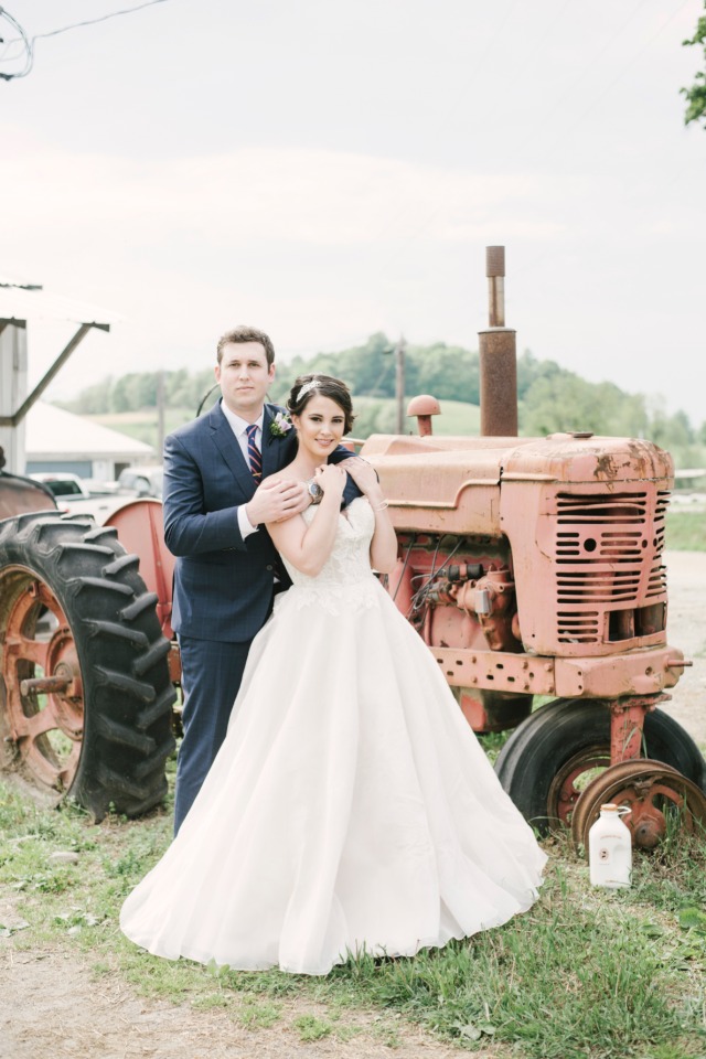Happy couple posing by vintage tractor for wedding photo