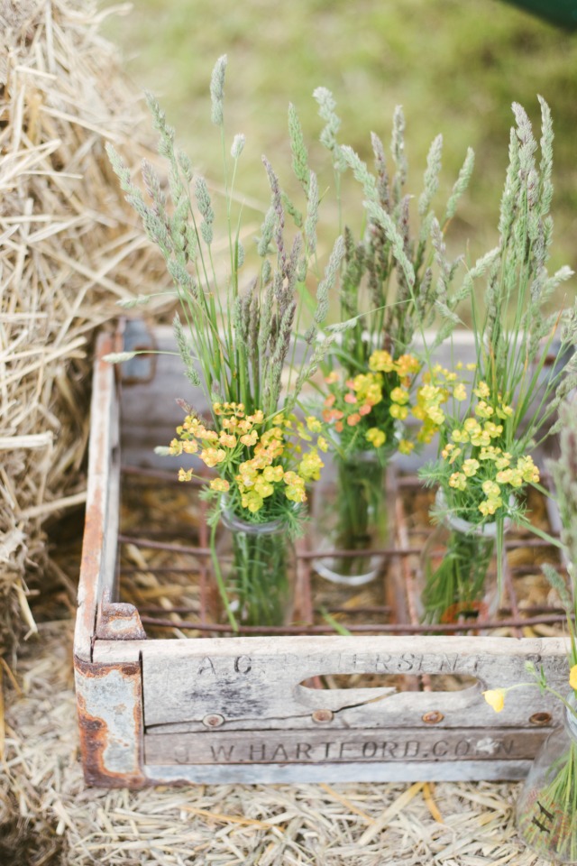 Rustic wooden crate with wildflowers in glass bottles
