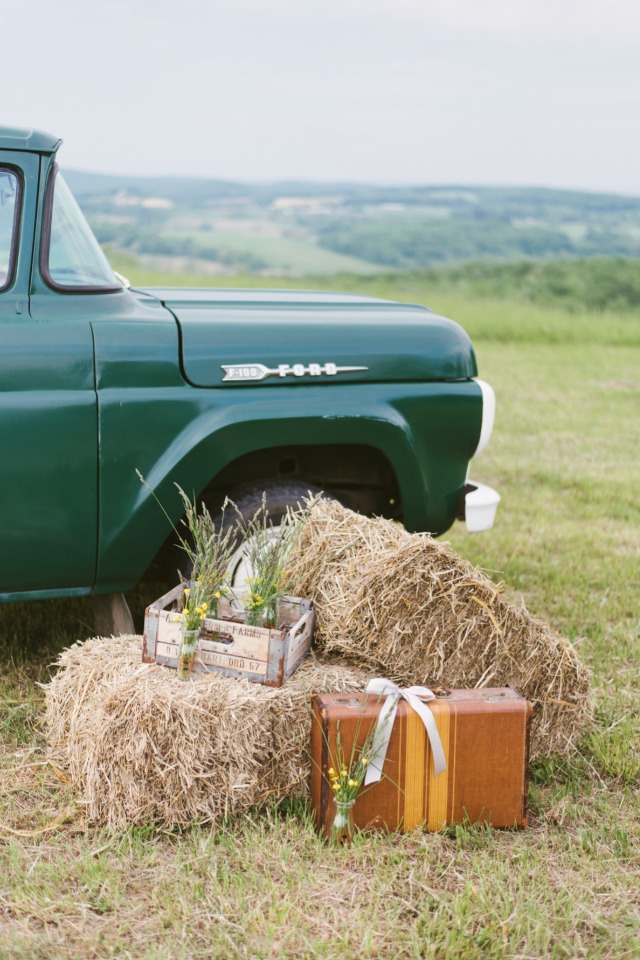 Vintage green truck with hay bales, suitcase, and flowers