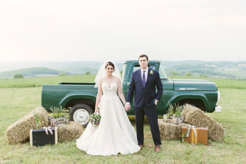 Happy couple posing by vintage truck for wedding photo