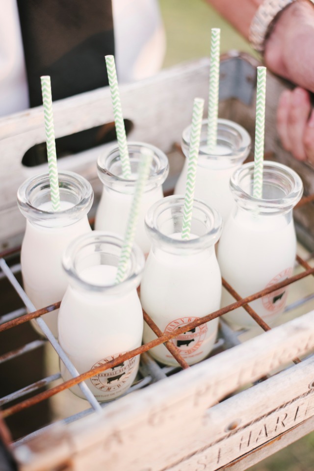 Cute milk bottles with straws in wooden crate for a party