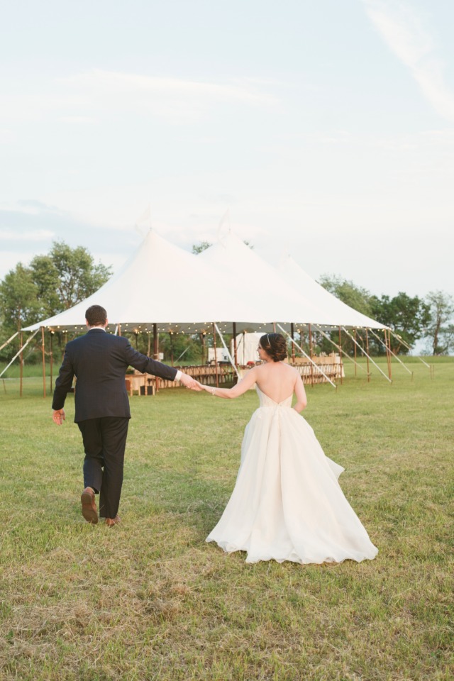 Bride and groom walking hand in hand towards wedding tent