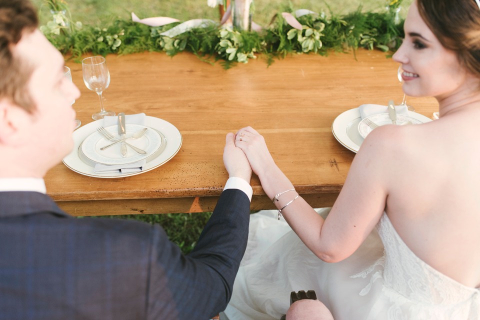Bride and groom holding hands at their wedding reception table