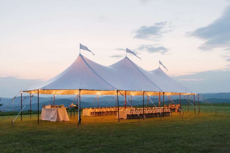 Outdoor wedding reception under a white tent with string lights